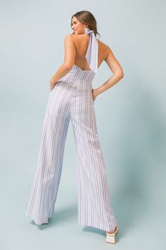 This ABSOLUTE EDGE WOVEN JUMPSUIT features a timeless shape that looks great on any body type. The surplice halter neckline with tie back and plunging back with zipper closure create a flattering silhouette, while the pleated front bottom and wide leg provide a flattering, comfortable fit. Details Self: 60% Polyester, 40% Cotton Lining: 100% Polyester Size & Fit - Model is 5`8" And Wearing Size Small - Measurements Taken From Size Small - Approx. Length: 45" Chic Summer Jumpsuits And Rompers With Back Zipper, Spring Backless Jumpsuit With Back Opening, Spring Halter Neck Jumpsuit With Tie Back, Backless Summer Jumpsuits And Rompers For Work, Backless Jumpsuits And Rompers For Summer Workwear, Blue Sleeveless Tie Back Jumpsuit, Jumpsuit Chic, Halter Jumpsuit, Long Romper