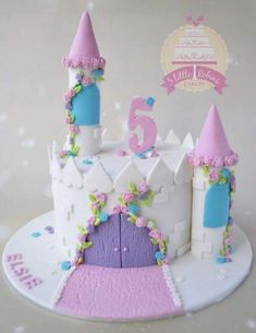 a white cake with pink and blue frosting on it's top is decorated like a princess castle