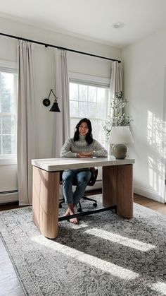 a woman sitting at a desk in front of a window