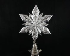 a silver snowflake on top of a metal cone with a star shaped decoration