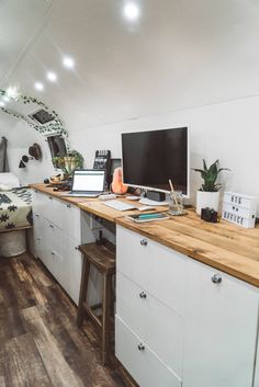 a desk with a computer on top of it next to a bed in a room