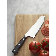 a large knife sitting on top of a cutting board next to tomatoes