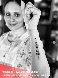 a woman with a tattoo on her arm holding up a peace sign in front of her face