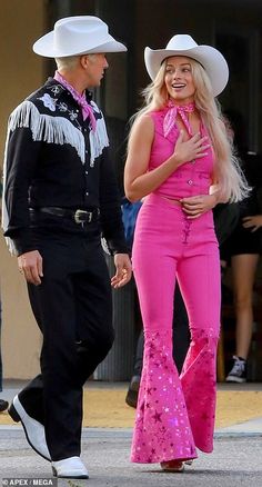 a man in a cowboy hat and pink pants talking to a woman with long blonde hair