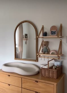 a dresser with a mirror, teddy bear and other items on the top shelf next to it