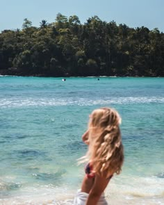 a woman standing on top of a sandy beach next to the ocean