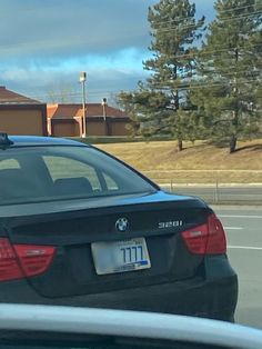 a black car parked in front of a building on the side of the road with a street sign