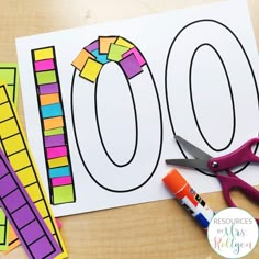 a table with scissors and paper cut out to look like the number 100 on it