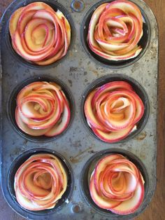 cupcakes with pink and yellow swirled icing in a muffin tin on a wooden table