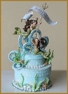 a blue cake decorated with an image of a mermaid holding a flag and sitting on top of it