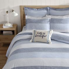 a bed with blue and white striped bedspread, pillows and lamp on nightstands