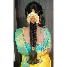 a woman with long hair wearing a yellow sari and holding a flower in her hair