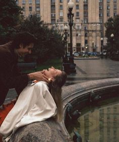 a woman laying on top of a rock next to a man