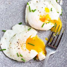 two fried eggs on top of a plate with a fork next to it and an egg in the middle