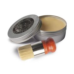 an orange and white brush next to a tin of lip bale on a white background