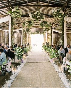 an outdoor ceremony with white flowers and greenery on the aisle, surrounded by candles