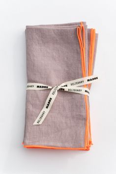 two napkins tied together with orange and white ribbon on top of each other in front of a white background