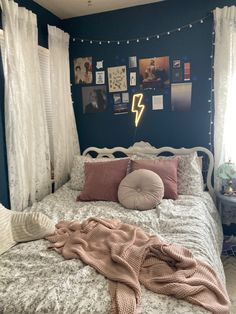 a bed with pillows and blankets on it in a room that is decorated with pictures