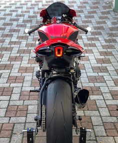 a red motorcycle parked on top of a brick road