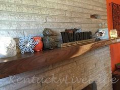 a mantel with candles and decorations on it in front of a brick wall that reads welcome