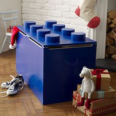 a blue toy chest sitting on top of a hard wood floor next to christmas presents