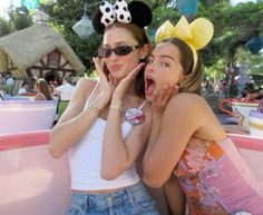 two girls in mickey mouse ears posing for the camera