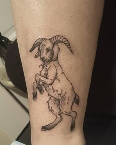 a small goat tattoo on the leg of a person's leg, with one arm extended