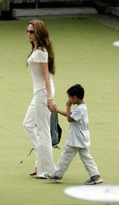 a woman holding the hand of a small boy