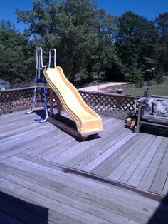 a yellow slide sitting on top of a wooden deck