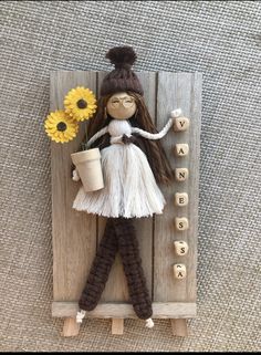 a doll is holding a potted plant and standing on a wooden board with letters