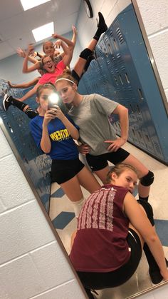 a group of girls standing in front of a mirror