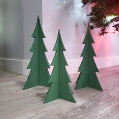 three green christmas trees in front of a white wall