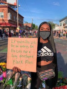 a woman wearing a face mask holding a sign