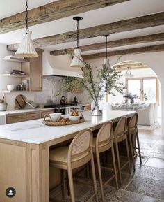 a kitchen with wooden beams and white counter tops next to a dining room table filled with chairs