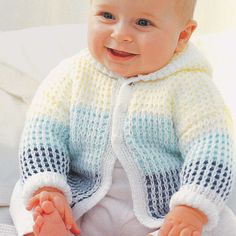 a baby sitting on top of a bed wearing a knitted sweater and smiling at the camera