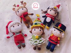 four knitted dolls are laying on a white sheet with snowflakes around them