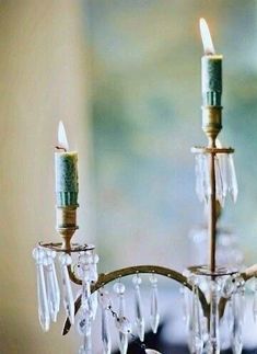 a chandelier with two candles on it and some crystal beads hanging from the top