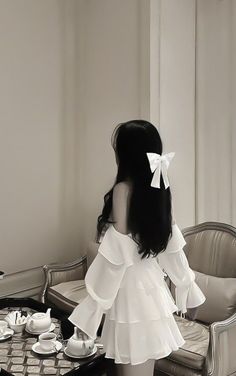 a woman standing in front of a table with tea cups and saucers on it