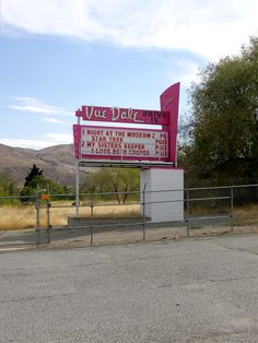 a large sign on the side of a road next to a fenced in area