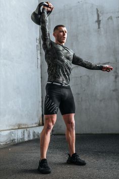 a man is holding his arms up in the air while wearing black shorts and a gray shirt