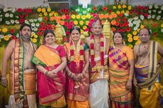 a group of people standing next to each other in front of a flower covered wall