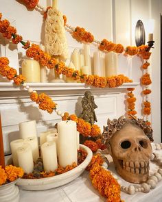 a table topped with candles and a skull head next to a bowl filled with flowers