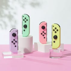 four nintendo wii game controllers on display in front of a white wall and pink background