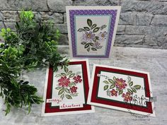 three cards with flowers on them sitting next to a potted plant and stone wall