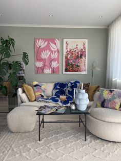 a living room filled with lots of furniture and paintings on the wall above it's coffee table