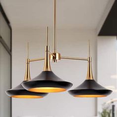 three black and gold lights hanging from a ceiling in a living room or dining room