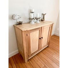 a wooden cabinet sitting on top of a hard wood floor next to a white wall