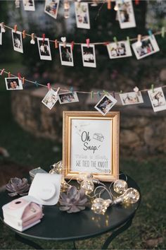 an old photo frame is sitting on top of a small table with photos hanging from it