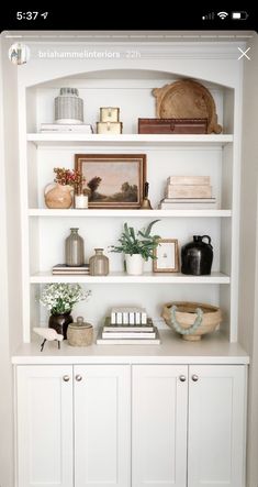 a white bookcase filled with lots of books and vases on top of it