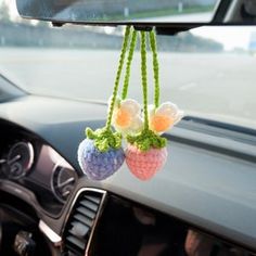 two crocheted balls hanging from the dashboard of a car, one with flowers on it